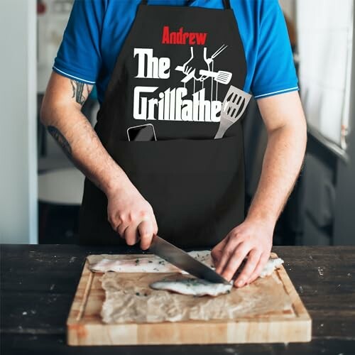 Person wearing 'The Grillfather' apron slicing fish on a cutting board.